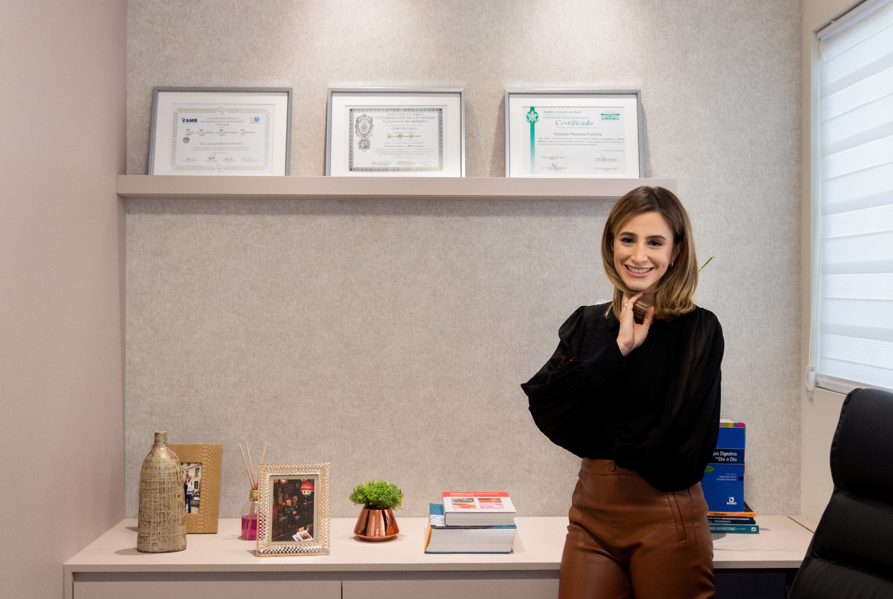 Doctor smiling in front of framed diplomas