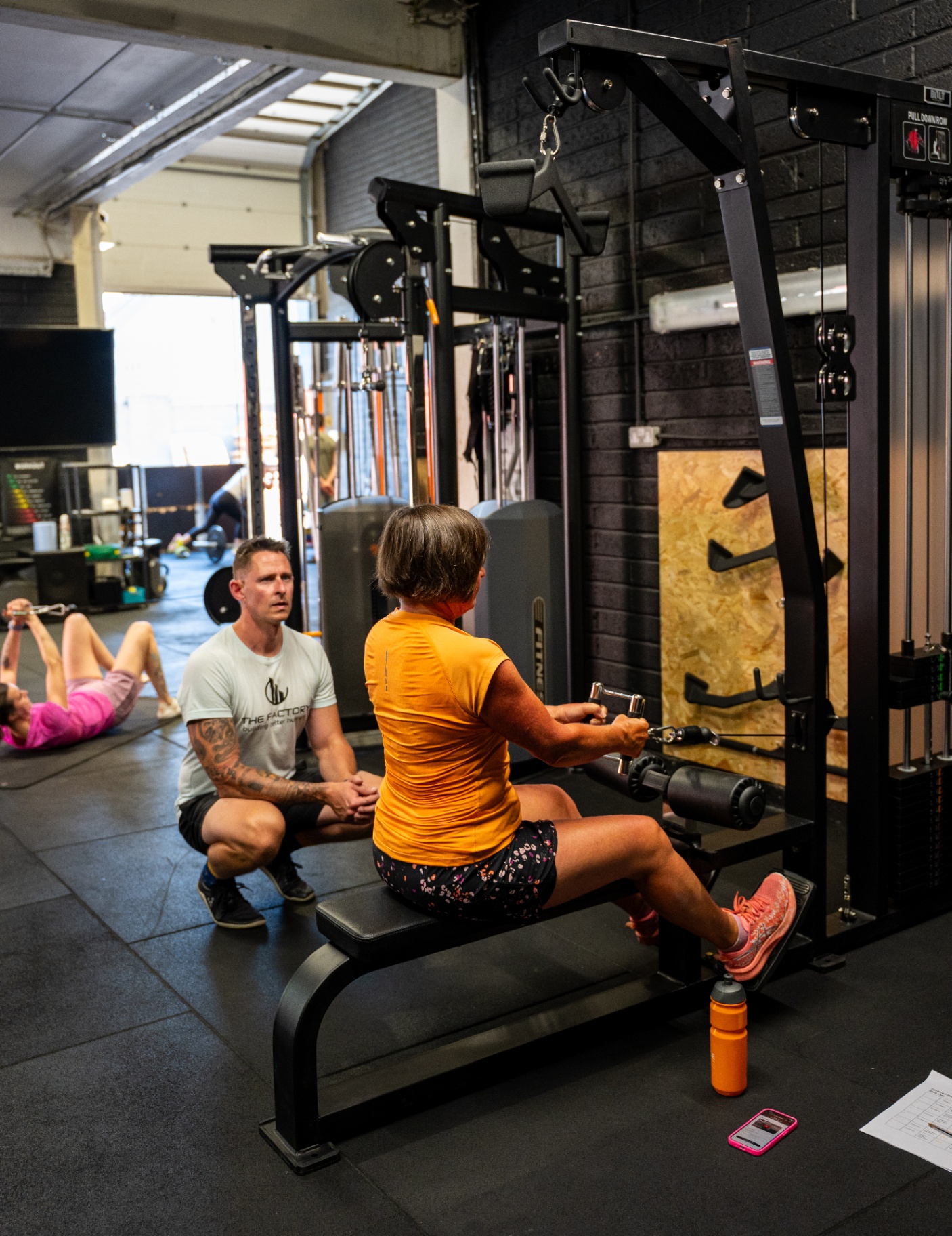 Coach guiding a client through a cable machine exercise