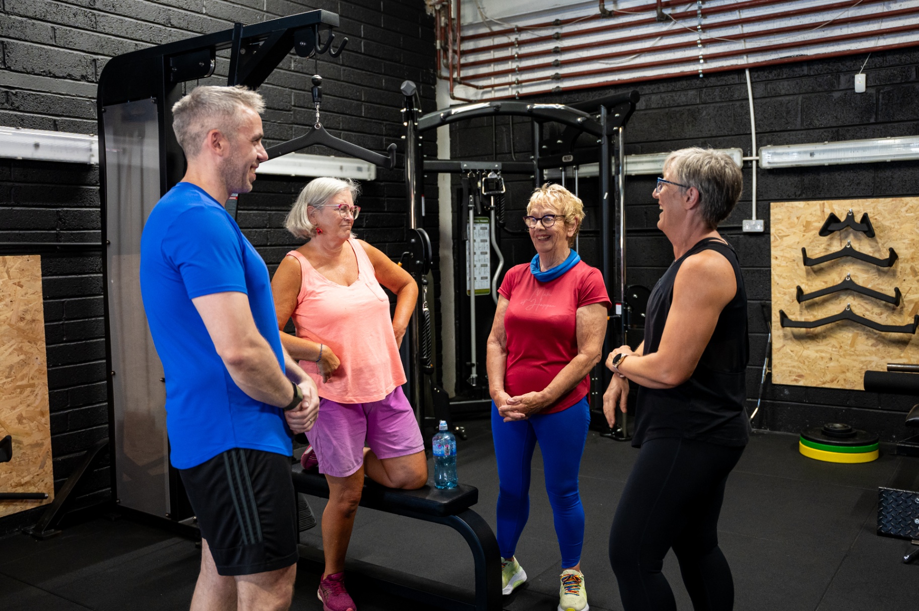Group of clients chatting with their coach at the gym
