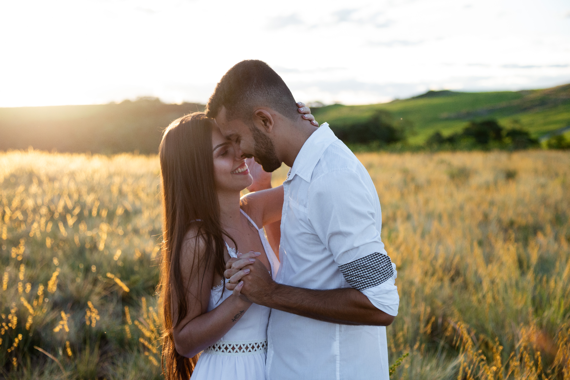 Couple sharing an intimate moment in a sunlit field