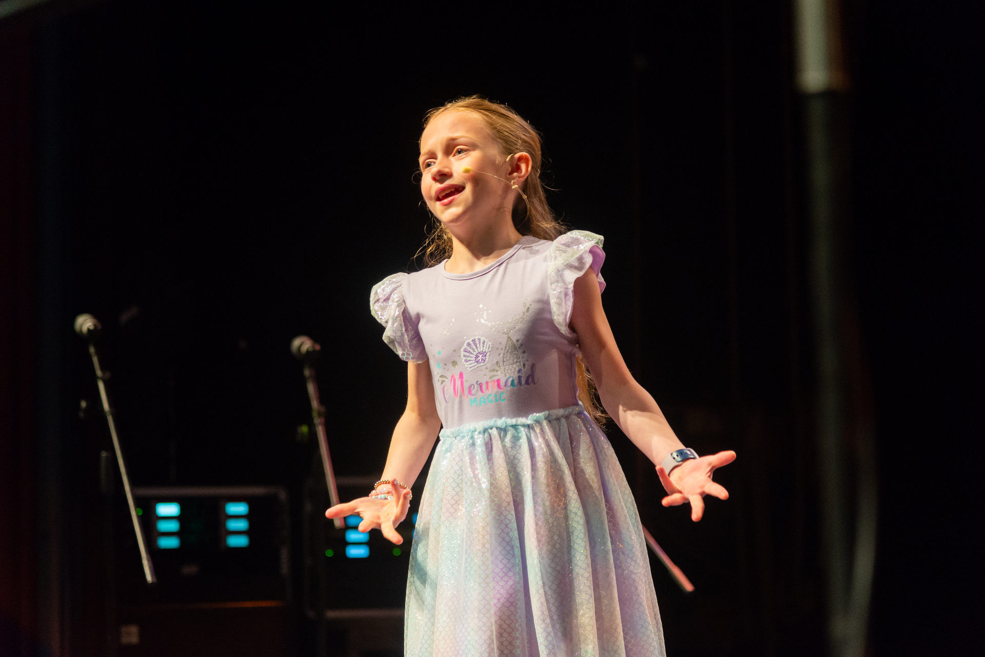 Young performer singing on stage in a sparkling dress