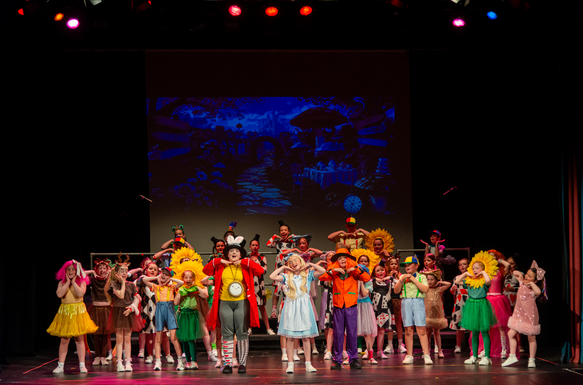 Full cast in colorful costumes performing Alice in Wonderland