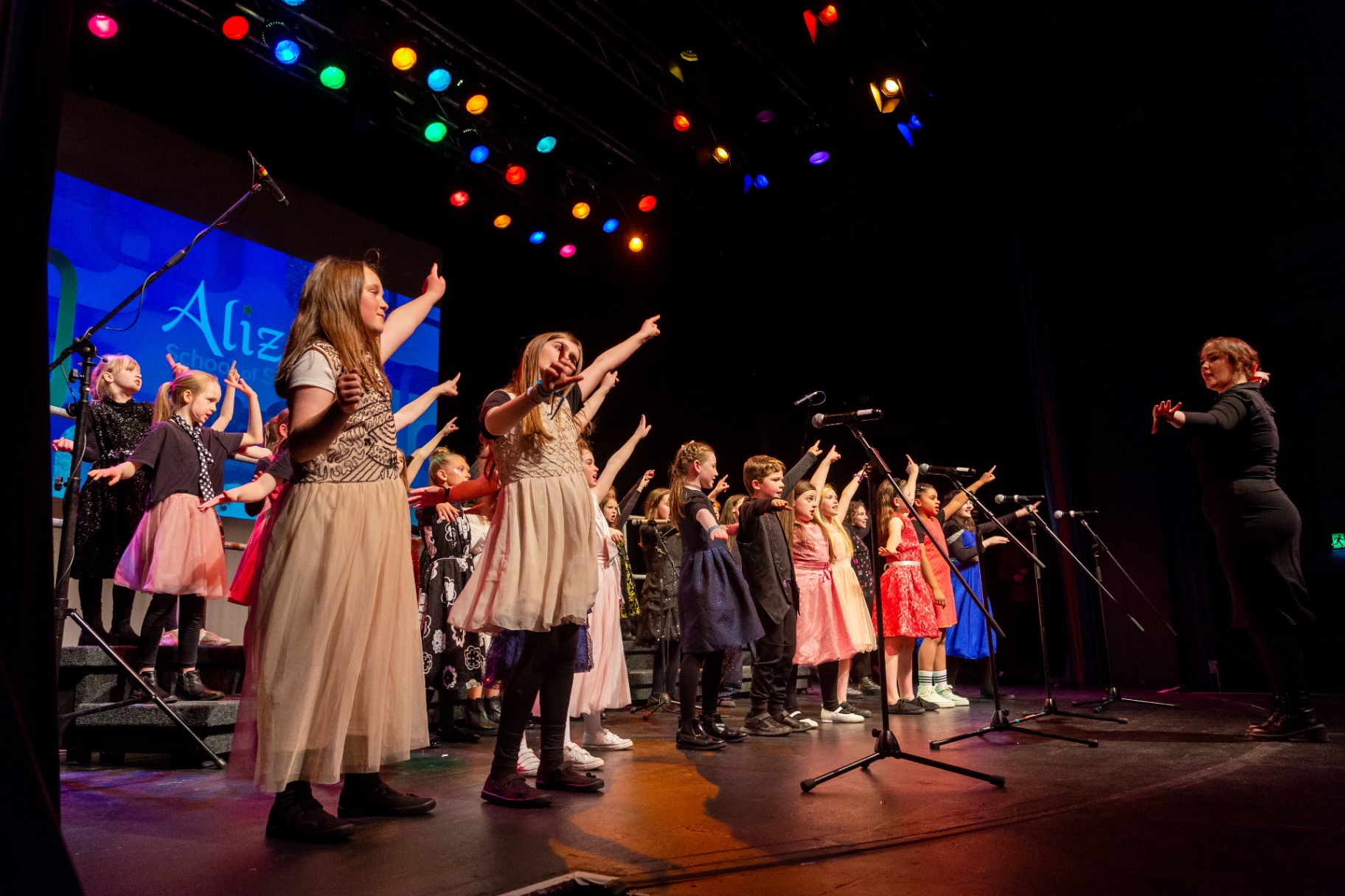 Children's choir performing on stage with colorful lights