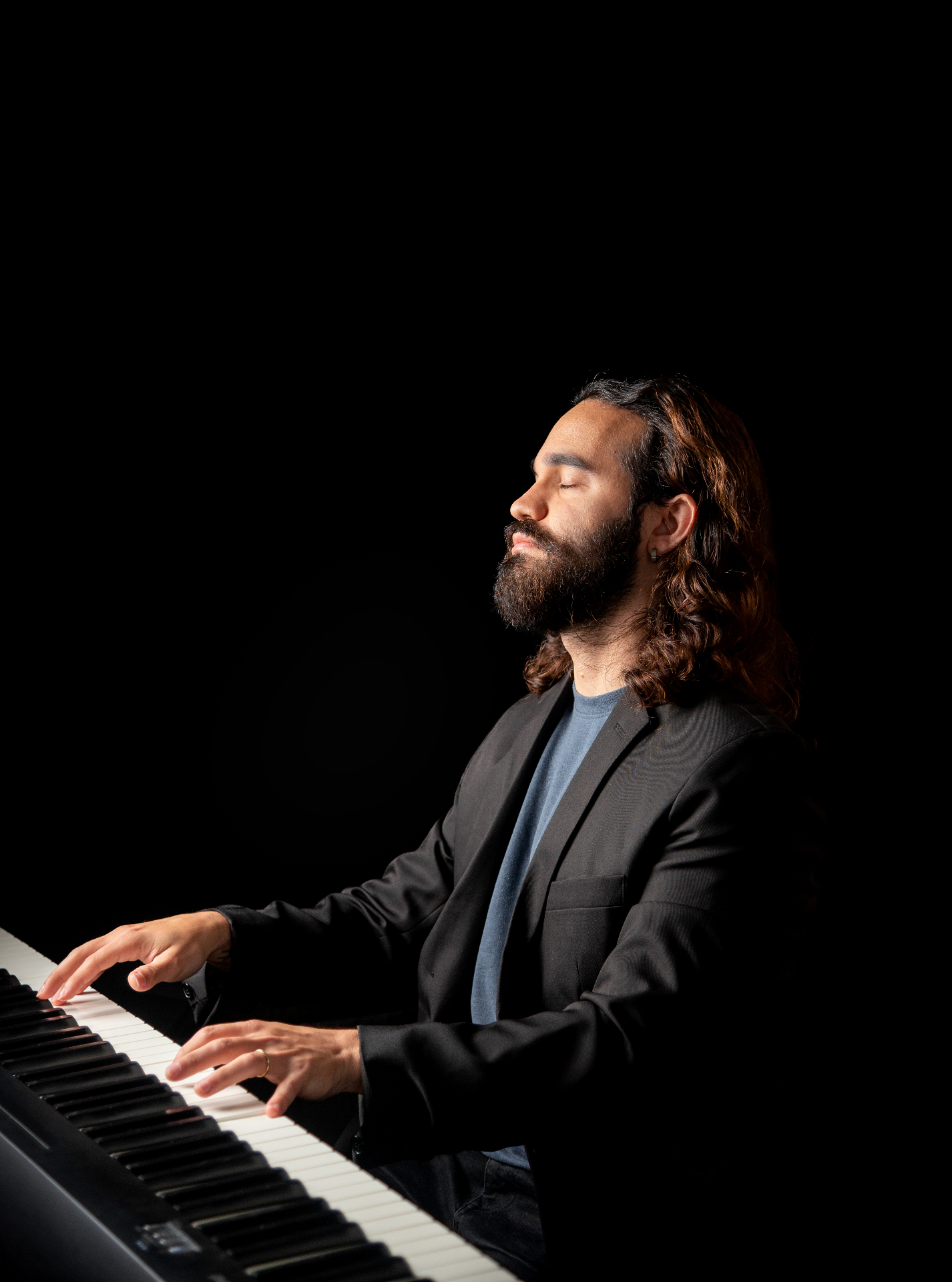 Pianist playing with eyes closed in dramatic lighting