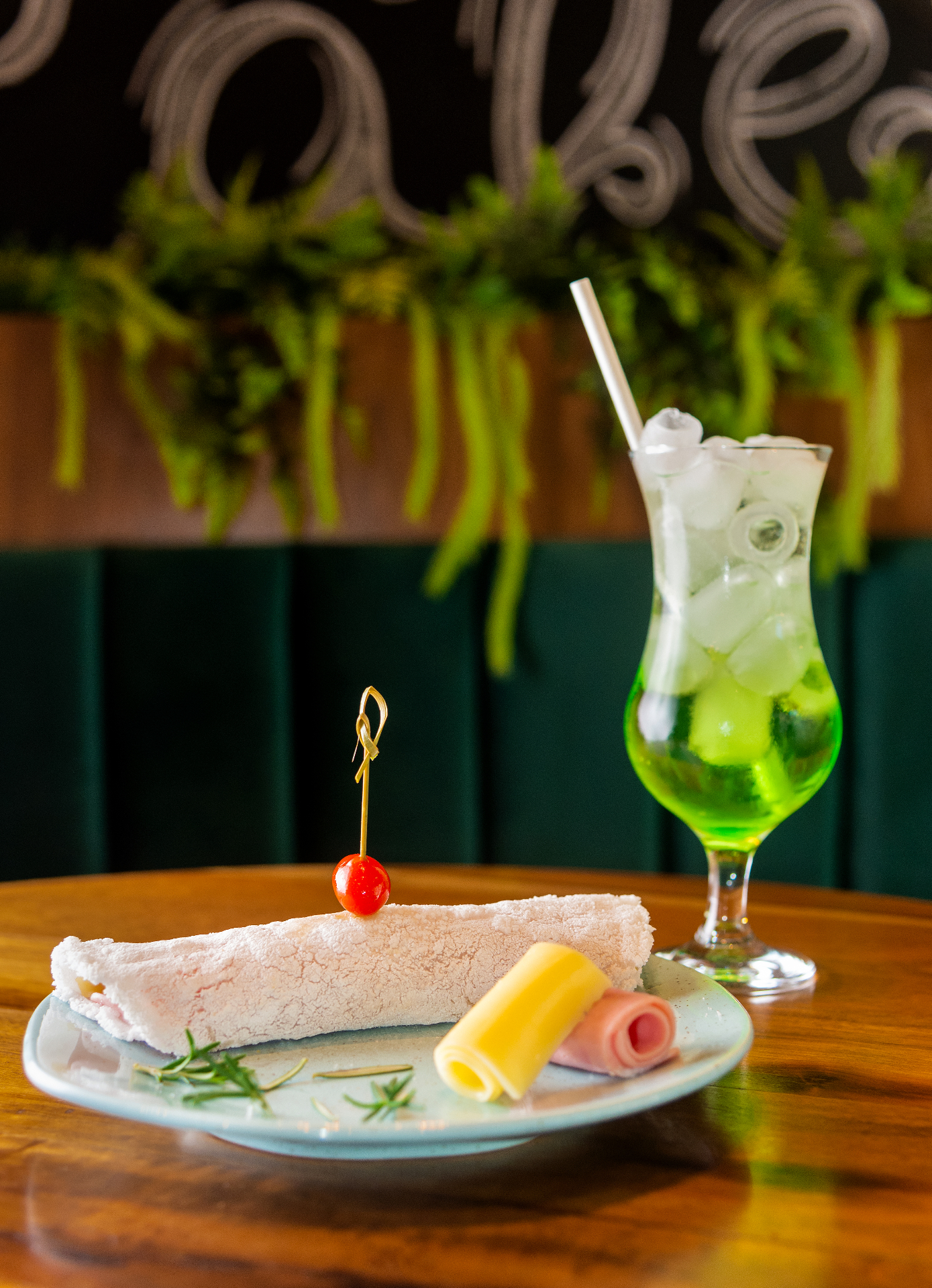 Tapioca crepe plated with colorful rolled garnishes and a bright green drink