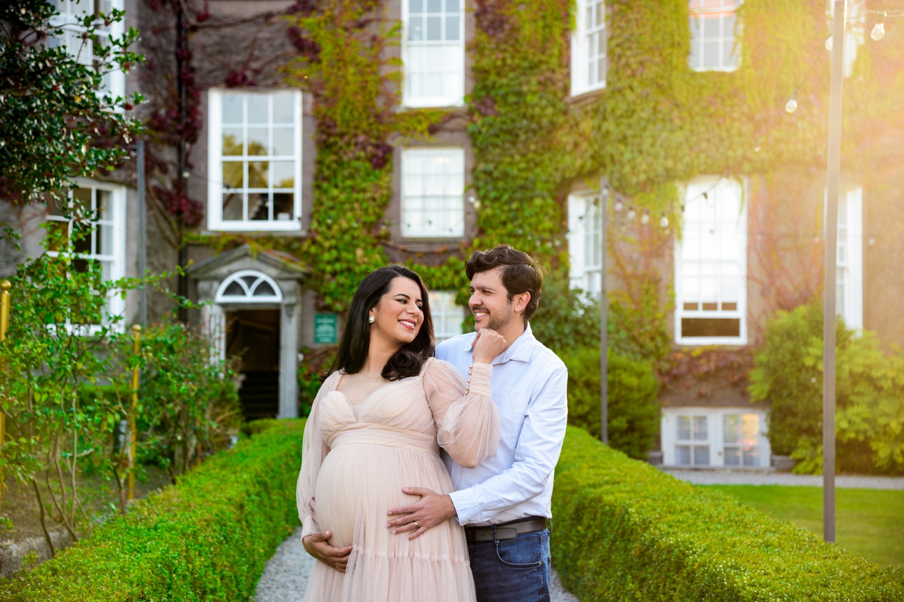 Expecting couple smiling together in a sunlit garden