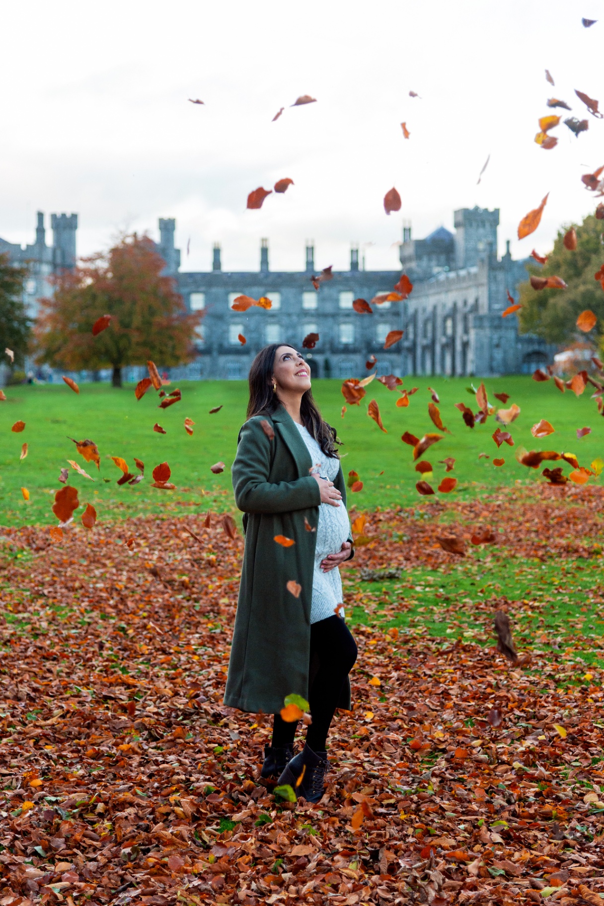 Pregnant woman surrounded by falling autumn leaves