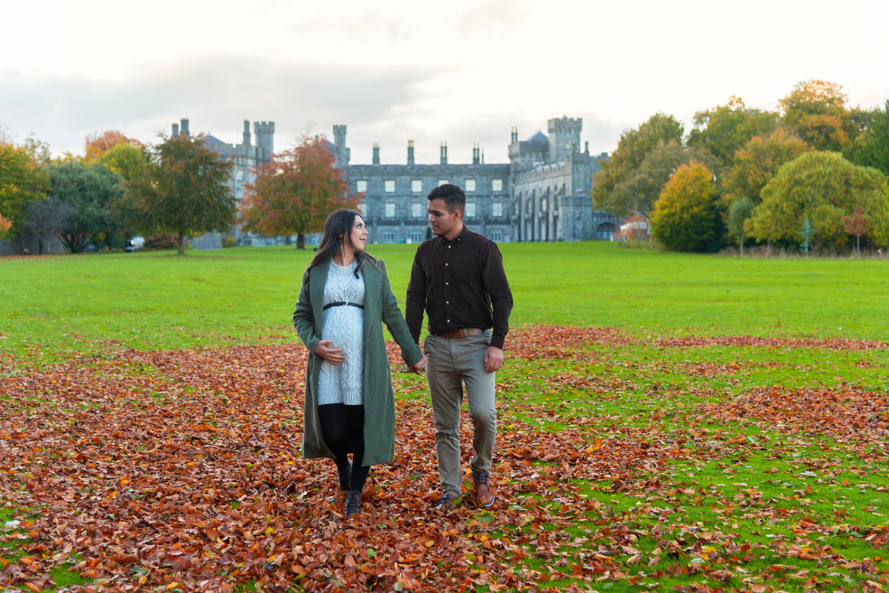 Expecting couple walking through autumn leaves