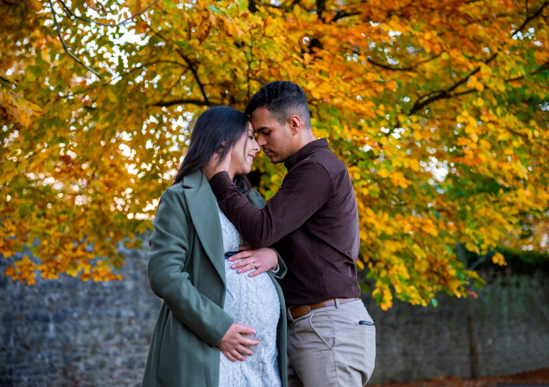 Expecting couple sharing a close moment under autumn trees