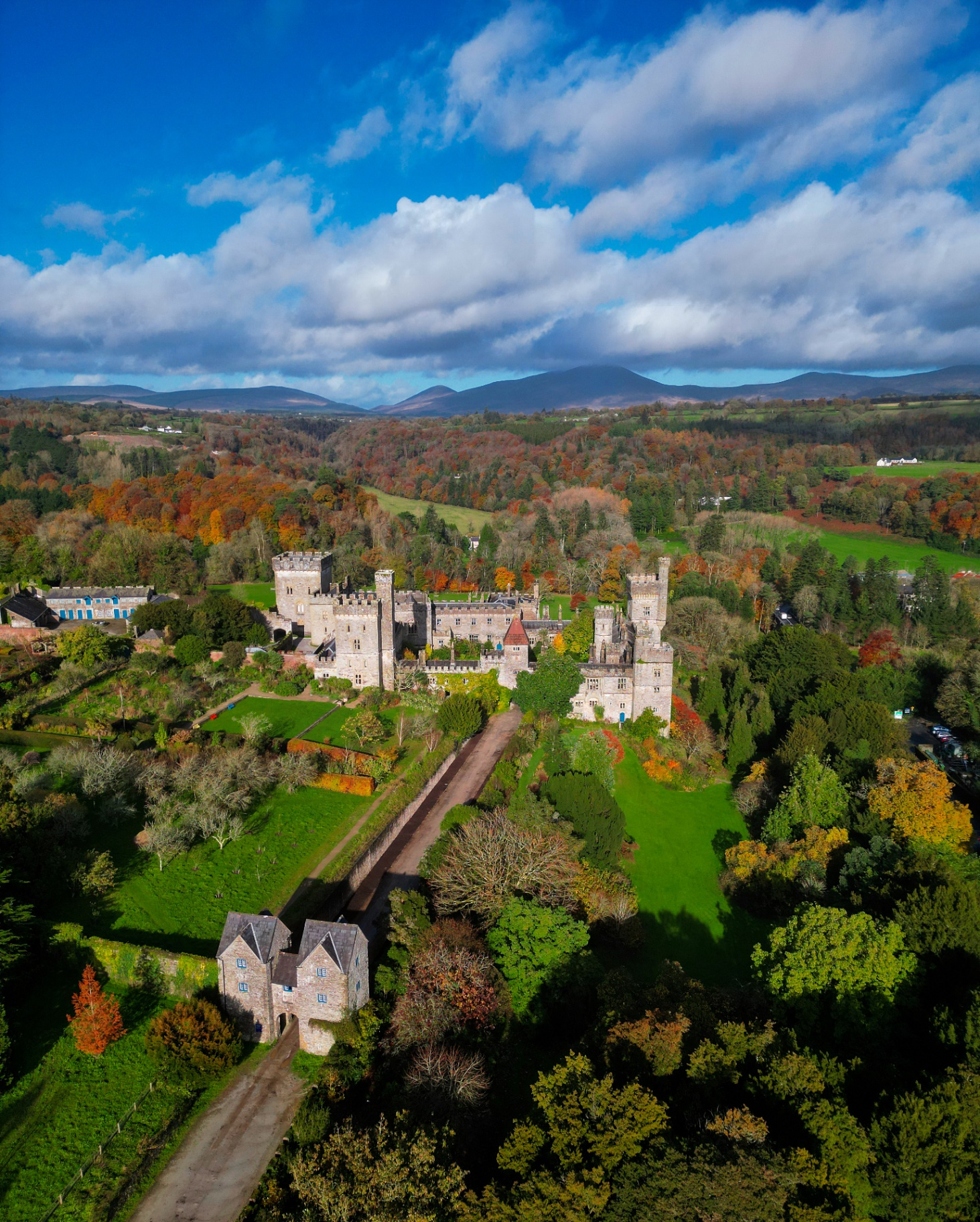 Aerial view of Lismore Castle surrounded by autumn woodland and mountains