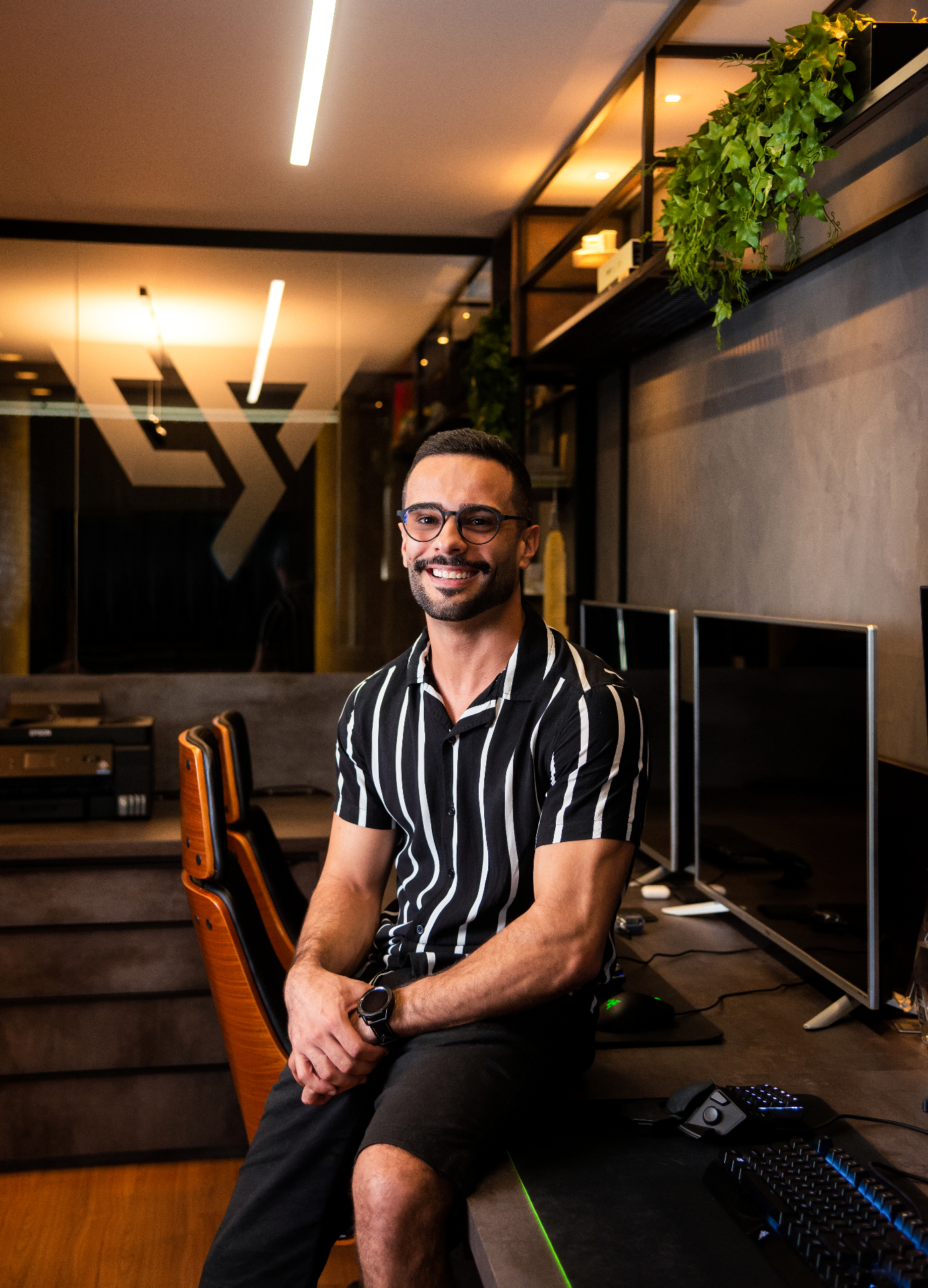 Smiling man in striped shirt seated in a modern office