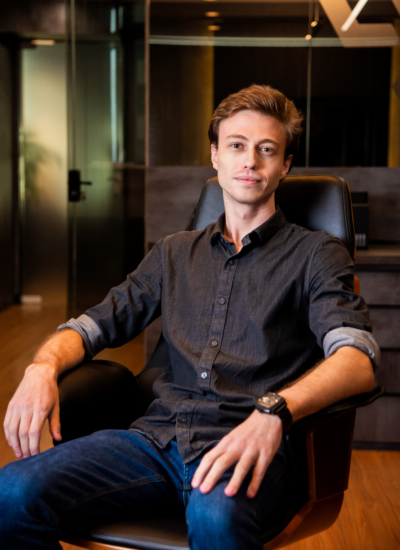 Professional portrait of a man in a dark shirt in an office chair