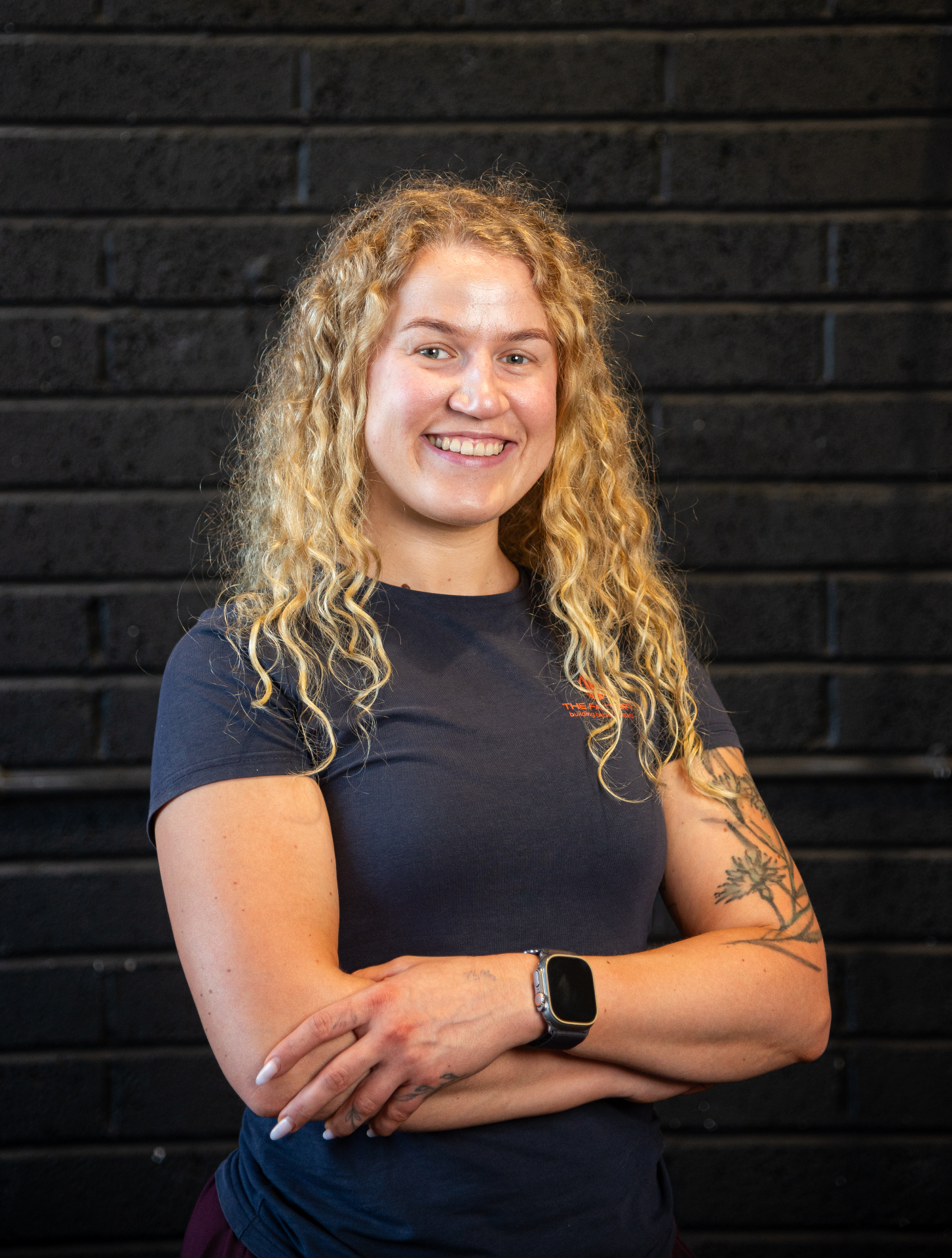 Smiling woman with curly blonde hair in a branded gym t-shirt